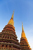 Nahaufnahme der verschnörkelten Tempelstrukturen (Stupa), die bei Sonnenuntergang in der buddhistischen Tempelanlage Wat Pho (Tempel des liegenden Buddhas) beleuchtet werden, Bangkok, Thailand, Südostasien, Asien