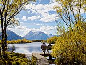 Couple on a bench looking out over Lake Wakatipu, Otago Region, South Island, New Zealand, Pacific