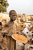 Boy wiith cow dung to clean the cows, Mundari tribe, South Sudan, Africa