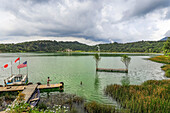 Boy fishing on dock by changing colour Lake Linow, a popular volcanic attraction and geothermal centre south of Tomohon city, Lake Linow, Tomohon, North Sulawesi, Indonesia, Southeast Asia, Asia