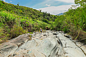 Walker on an old lava flow, now a smooth eroded river bed and hiking trail to Lokon volcano, near Tomohon city, Gunung Lokon, Tomohon, North Sulawesi, Indonesia, Southeast Asia, Asia