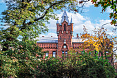 Low angle of traditional building of Municipal Headquarters of the State Fire Service surrounded by trees, Krakow, Poland, Europe