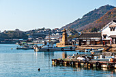 Blick auf den kleinen Fischerhafen von Tomonoura mit dem berühmten steinernen Leuchtturm und dem blauen Wasser, Tomonoura, Honshu, Japan, Asien