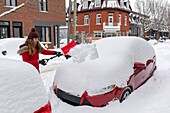 Kanada, Provinz Québec, Montreal, das Viertel Plateau-Mont-Royal nach einem Schneesturm, eine Frau schaufelt ihr Auto frei