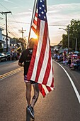 Vereinigte Staaten, Neuengland, Massachusetts, Cape Ann, Gloucester, Gloucester Horribles Traditional Parade, 3. Juli, Mann marschiert mit US-Flagge