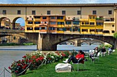 Italy, Tuscany, Florence, listed as World Heritage by UNESCO, the Ponte Vecchio seen from the Societa Canottieri Firenze (Florence Rowing Club), club members having a rest on the edge of the Arno River