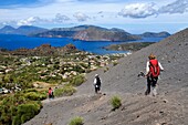 Italy, Sicily, Aeolian Islands, listed as World Heritage by UNESCO, Vulcano Island, hikers on the flanks of the crater of volcano della Fossa, Lipari Island in the background