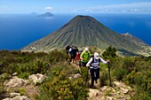 Italy, Sicily, Aeolian Islands, listed as World Heritage by UNESCO, Salina Island, hikers at the summit of the ancient volcano Monte Fossa delle Felci with the twin volcano Monte dei Porri, the islands of Filicudi and Alicudi in the background