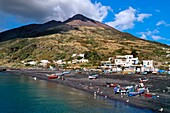 Italien, Sizilien, Äolische Inseln, von der UNESCO zum Weltnaturerbe erklärt, Insel Stromboli, Fischer am Strand von Scari und der aktive Vulkan Stromboli im Hintergrund (Luftaufnahme)