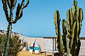 Marokko, Oued Ed-Dahab, Dakhla, Ocean Vagabond Resort, Surfer am Strand in der Nähe einer luxuriösen Öko-Lodge in einem tropischen Wüstenklima