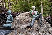 Ireland, Dublin, Merrion Square, memorial tribute to Irish author Oscar Wilde known for his dissolute life, set of statues nude woman and writer nonchalantly lying on a rock in full green and red suit jacket