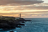 Spanien, Kanarische Inseln, La Palma, Blick auf einen Leuchtturm gegen das Licht am Meer bei Sonnenuntergang