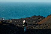 Spanien, Kanarische Inseln, La Palma, Wanderer auf einem Wanderweg in einer wüstenhaften und vulkanischen Umgebung bei Sonnenaufgang