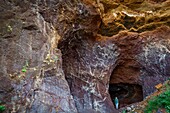 Spanien, Kanarische Inseln, La Palma, Touristen auf einem Wanderweg unter einem Gewölbe aus Vulkangestein am Meer