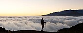 Spanien, Kanarische Inseln, La Palma, Silhouette eines Wanderers vor einem Wolkenmeer bei Sonnenuntergang