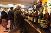 Vereinigtes Königreich, Schottland, Shetlandinseln, Mainland, Lerwick, Mann im Kilt in einem Pub und Bierflaschen im Vordergrund