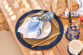 A neatly presented breakfast place setting on a terrace table with blue and white tones, capturing a relaxed, coastal dining ambiance