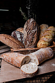 A selection of fresh, handmade sourdough bread, with inviting textures, dusted with flour, and displayed in a rustic basket setting.