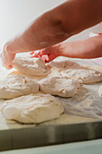 An anonymous chef prepares fresh pizza dough, hands working delicately on the flour-coated surface