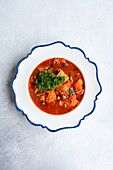 This image features a hearty serving of traditional Ukrainian borscht, a beetroot soup with chunks of meat and a dollop of sour cream, garnished with parsley