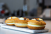 Süße vegane Berliner mit Zuckerkruste auf einem Brett und Sahne auf einem Tablett in einer Bäckerei