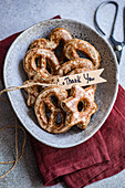 Draufsicht auf selbstgebackene sternförmige Lebkuchen, mit Zucker bestäubt und in einer gesprenkelten Keramikschale präsentiert, begleitet von einem Dankesschild, alles auf einer roten Serviette.