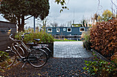 Modern bicycles parked near house on cobblestone yard near trees in suburb area of city in autumn day