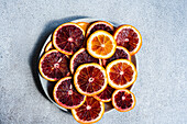 Top view of vibrant Sicilian blood orange slices arranged on a circular plate, showcasing their juicy segments and rich color contrast.