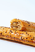 Two pieces of golden-brown veal puff pastry topped with flax seeds, freshly baked and set against a white background.