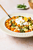 Image of a plate of roasted squash topped with dollops of mayonnaise and drizzled green pesto, garnished with seeds.