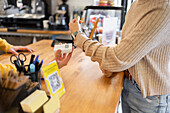 Customer making a contactless payment with a smartwatch at a café counter.