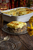 Hausgemachte Fleischpastete mit goldbraunem Kartoffelpüree, serviert auf einem rustikalen Holztisch.