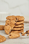 A delectable stack of chocolate chip cookies with crumbs scattered on a rustic wooden surface, seen from a top view