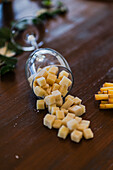 Spilled cheese cubes from a tipped wine glass on a wooden table