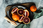 A top view of juicy blood oranges, freshly cut and displayed on a dark plate with a rustic wooden board background