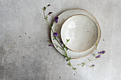 Top view of a minimalist summer table setting, featuring a vintage plate and wild alfalfa flowers adding a touch of nature's elegance.