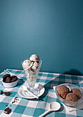 Ice cream cones on a white plate with sandwich biscuits beside on a blue checkerboard tablecloth, evoking a playful dessert scene