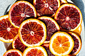 From above of vibrant slices of fresh Sicilian blood oranges arranged on a table, showcasing the deep red hues typical of this citrus fruit variety.