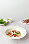 Plate of roasted radishes drizzled with green tahini sauce, garnished with parsley, photographed on a white table.