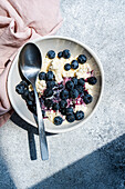 A nutritious breakfast featuring a bowl of cottage cheese topped with organic blueberry jam and fresh blueberries, served with a silver spoon