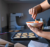 Capturing the essence of Halloween with homemade cookies, hands expertly icing ghost and pumpkin shapes against a modern kitchen backdrop