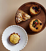 Top view of a delectable selection of pastries displayed on wooden and ceramic plates, featuring various textures and fillings, for a mouthwatering visual feast.