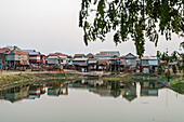 Stilt homes built on the riverbank, reflecting cultural architecture in a small, serene Cambodian village.