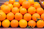 A vibrant display of ripe oranges arranged neatly on a market stall, showcasing their juicy and fresh appeal