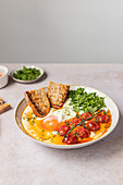 Succulent Turkish eggs perched on a bed of creamy Greek yoghurt, dressed with a spicy bowl sauce and garnished with vibrant parsley and juicy cherry tomatoes