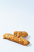 Two pieces of golden-brown veal puff pastry topped with flax seeds, freshly baked and set against a white background.