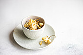 A tasteful arrangement of dried roses nestled in a textured ceramic bowl and plate, set against a soft white background