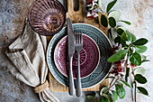 Top view beautifully arranged dining table featuring Feijoa accents, with detailed ceramic dishware in purple and grey tones Exotic Feijoa flowers and leaves add a unique touch to the rustic background, enhancing the meal's ambiance