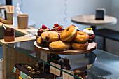 Various vegan sweet donuts and cakes on wooden tray placed on counter in bakery