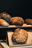 Artisan sourdough bread freshly baked, displayed on wooden shelves, showcasing the crusty exterior and artisanal texture.